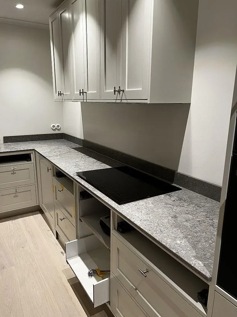 Grå köksbänkskiva i Caesarstone Turbine Grey med infälld induktionshäll och öppna stommar under montering i ett kök i Västra Frölunda.