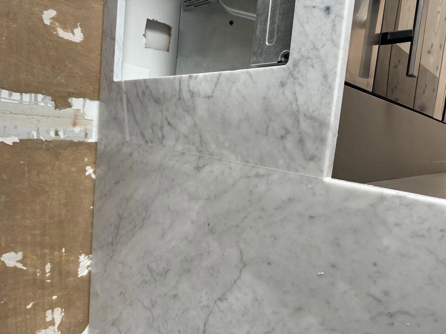 Närbild av kant och hällurtag i matt Carrara C marmor i ett kök i Borås.