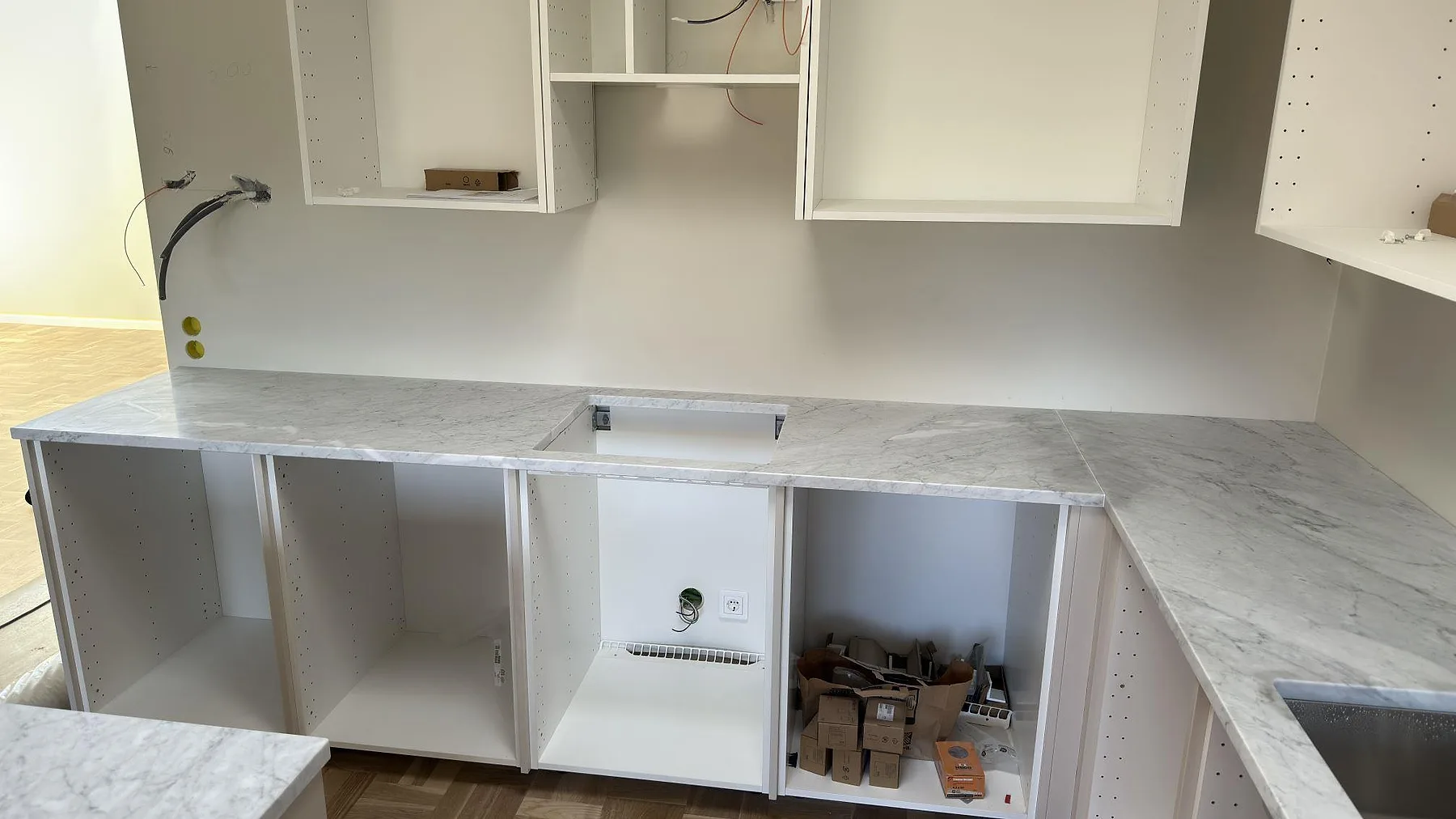 Rak bänkskiva i matt Carrara C marmor med urtag och öppen köksstomme under montering i Djursholm.