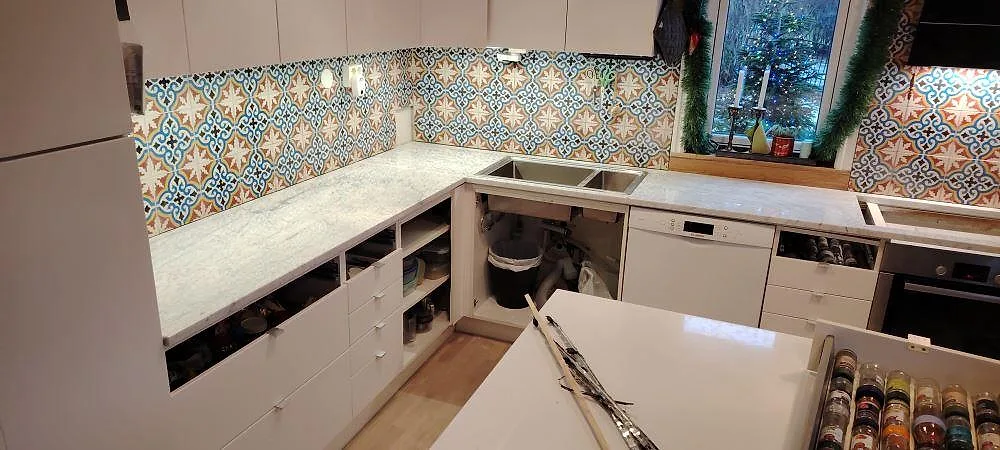 L-formad köksbänkskiva i Carrara C marmor, 30 mm med matt och polerad finish angiven, under montering med öppen diskzon och kaklat stänkskydd i Ekerö.