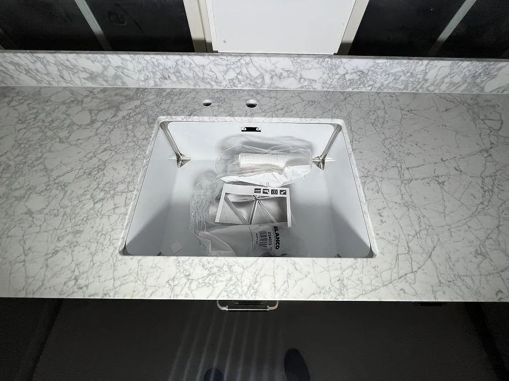 Underlimmad ho i en matt Carrara C köksbänkskiva med grå marmorådring och stänkkant i Enebyberg.