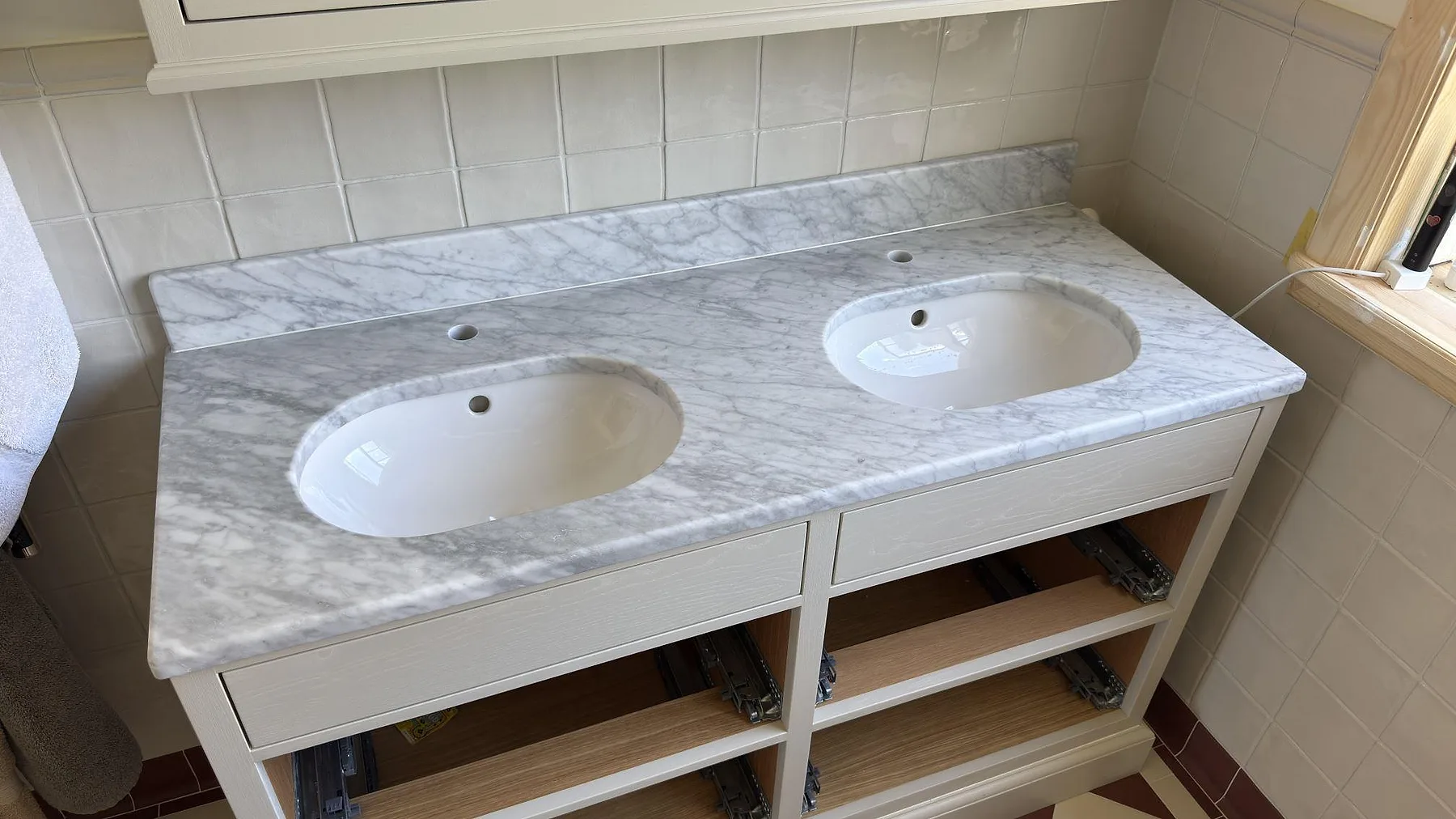 Carrara C marmor i matt yta som dubbel tvättställsbänk med borrade blandarhål och marmorstänkkant i ett badrum i Enskededalen.