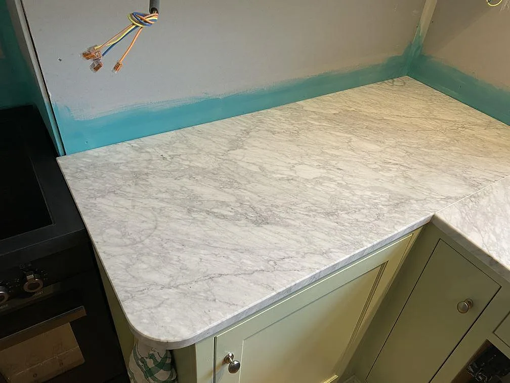 Köksbänkskiva i vit Carrara C marmor med matt yta i ett kök under montering i Falsterbo.