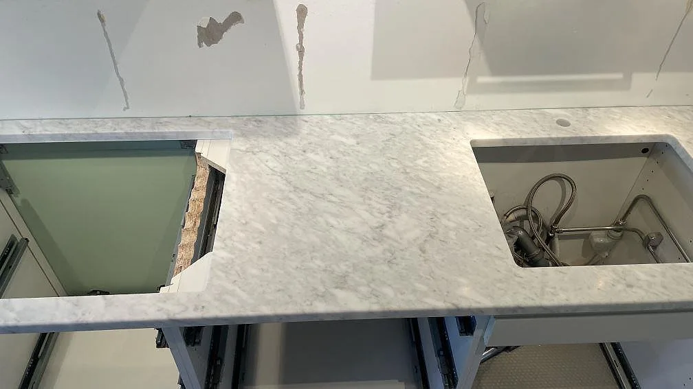 Detalj av matt Carrara C marmor på väggbänk med förberedda urtag och tät grå ådring i Falsterbo.