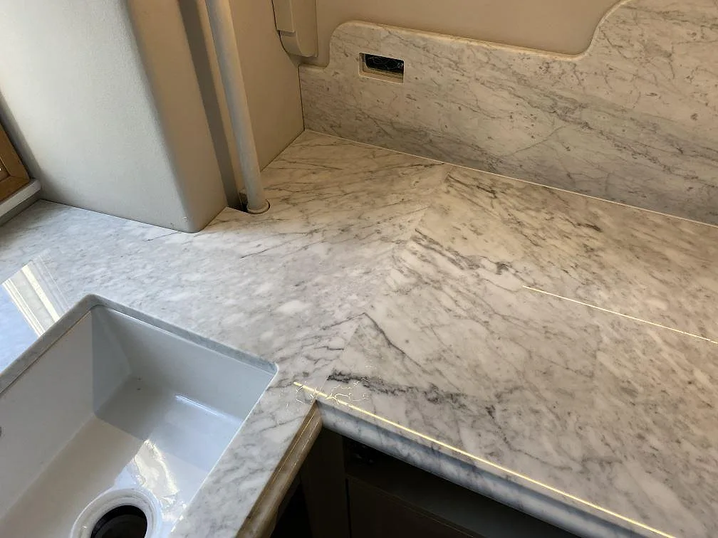 Detalj av Carrara C-marmor, polerad köksbänkskiva med vit diskho och uppvikt stänkkant i Frederiksberg C.