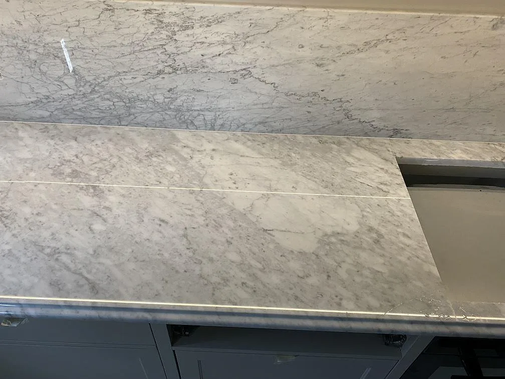 Detalj av hälluttag i polerad Carrara C-marmor med matchande stänkkant i Frederiksberg C.