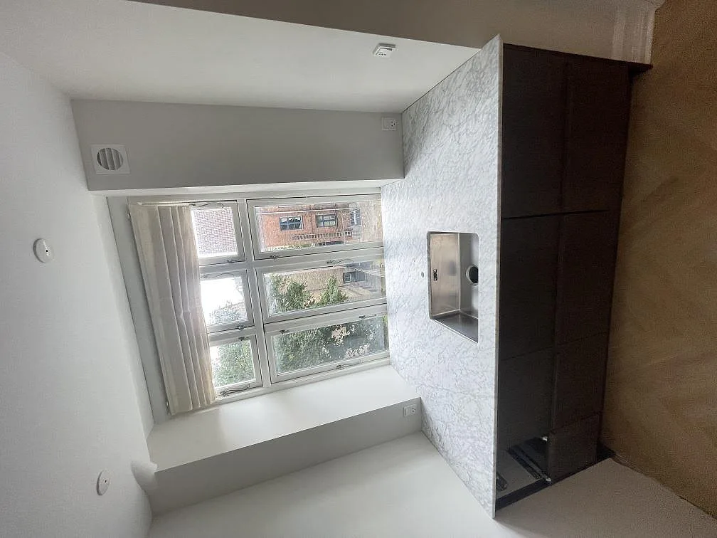 Matt köksbänkskiva i Carrara C marmor med svart induktionshäll i en kompakt halvö med mörka underskåp i Frederiksberg C.