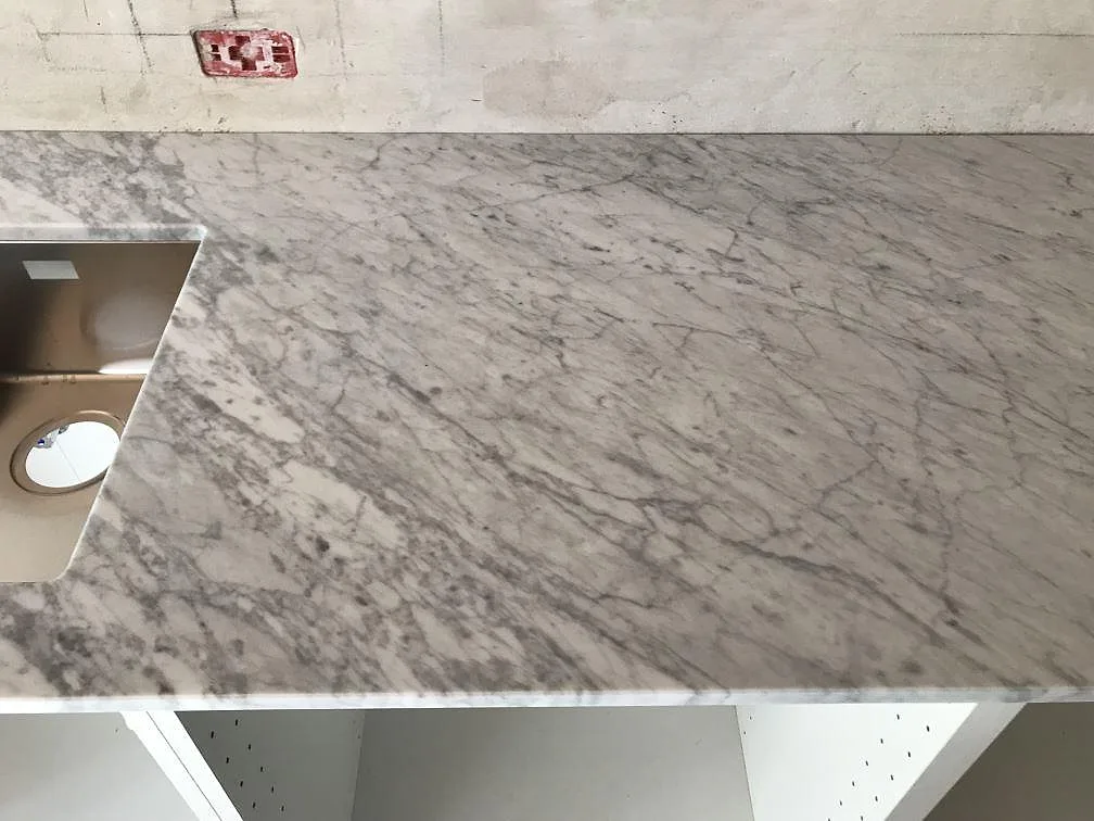 Köksbänkskiva i Carrara C marmor sedd uppifrån med urtag för underlimmad diskho och fin ådring, i Gilleleje.