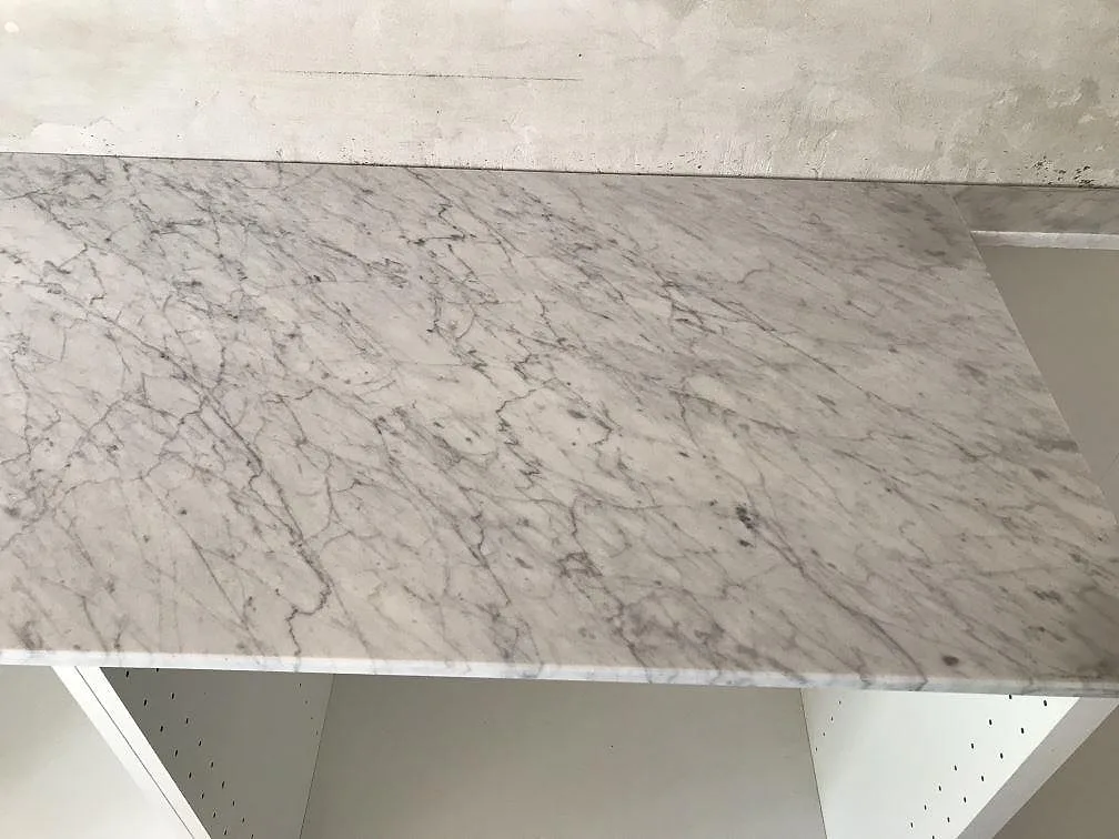 Vit Carrara C marmor med grå ådring som köksbänkskiva mot vitt kakel i ett kök i Gilleleje.