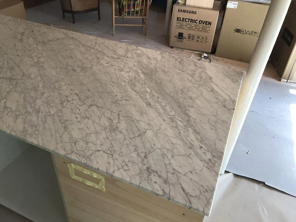 Hörn av köksö i Carrara C marmor med tydlig grå ådring, matt yta, i ett kök i Gilleleje.