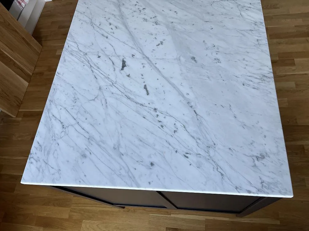 Topptagen bild på köksbänkskiva i Carrara C marmor med levande grå ådring och matt finish i ett kök i Göteborg.