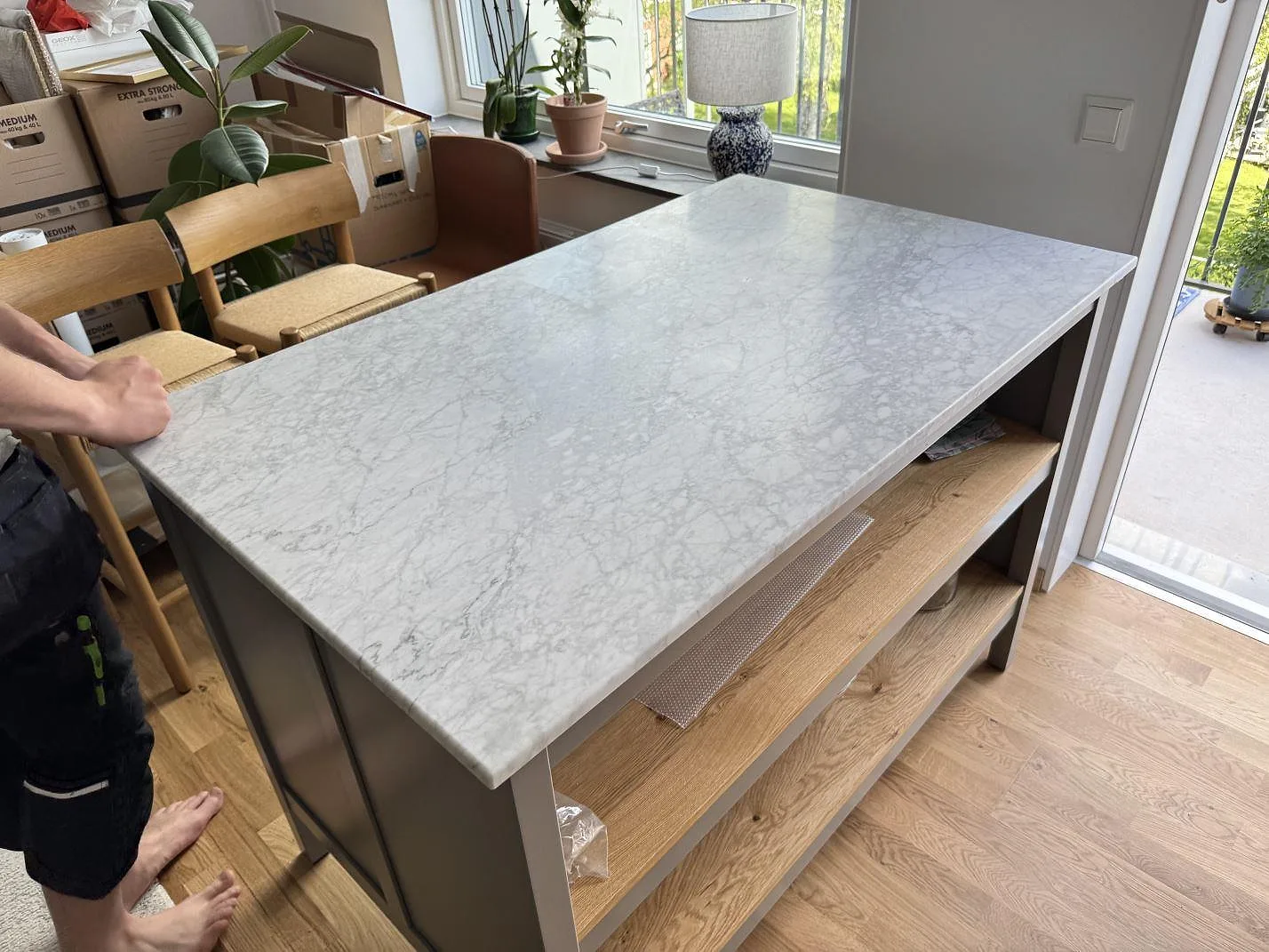Köksö med bänkskiva i Carrara C marmor, matt yta och mjuk grå ådring i ett kök i Göteborg.