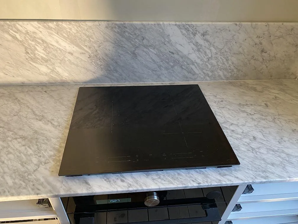 Carrara C köksbänkskiva i matt marmor med svart häll och matchande stänkskydd i Göteborg.