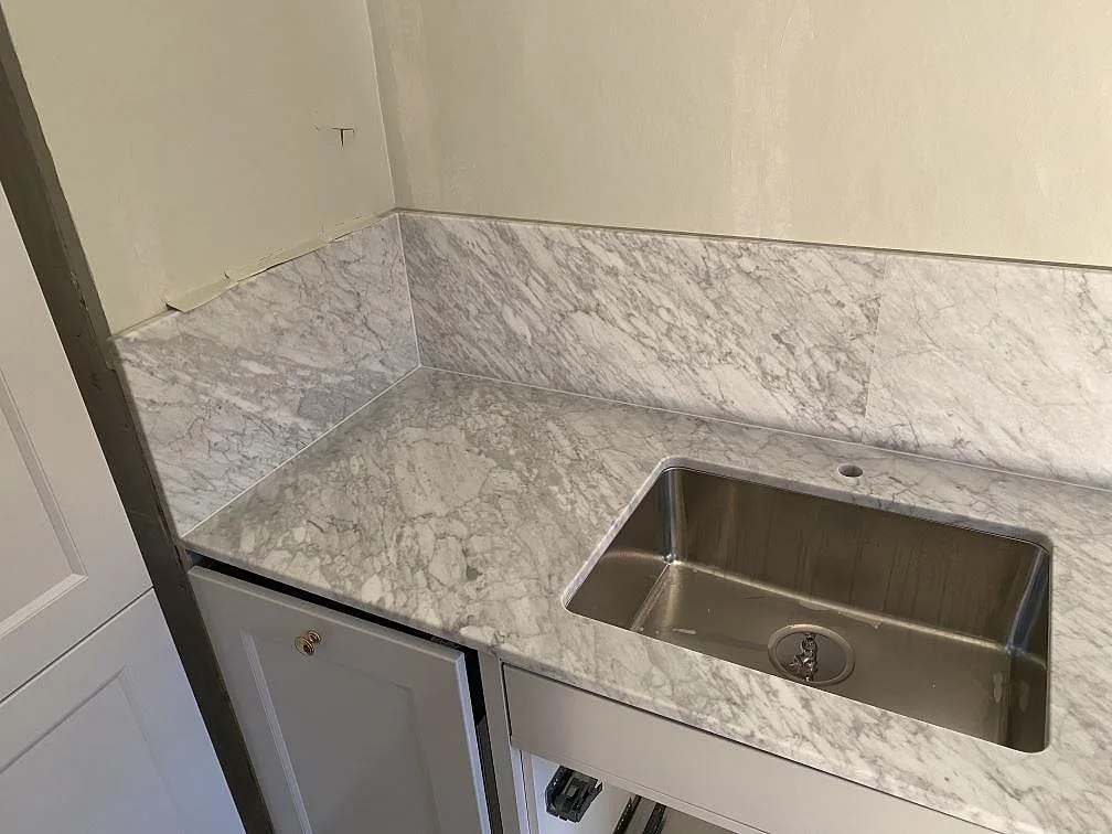 Matt Carrara C marmorbänkskiva med rostfri diskho och uppvikt stänkkant under montering i Göteborg.
