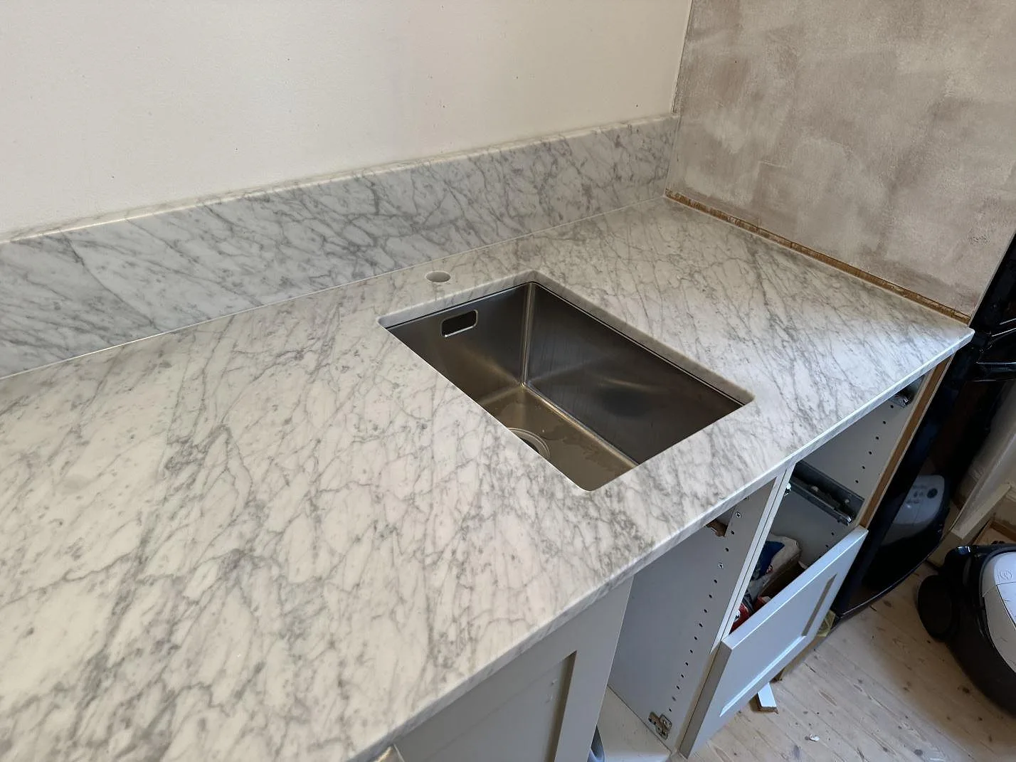 Polerad Carrara C marmorskiva med rostfri underlimmad diskho, blandarhål och uppvikt stänkskydd i kök i Göteborg.