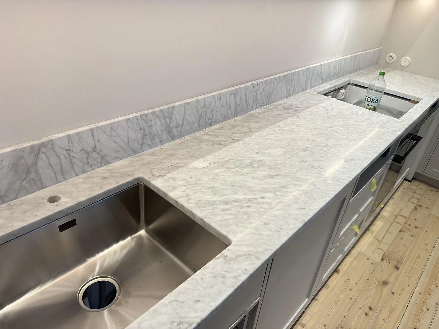 Köksbänkskiva i matt Carrara C marmor med uppvikt stänkkant, rostfri diskho och hällöppning i Göteborg.