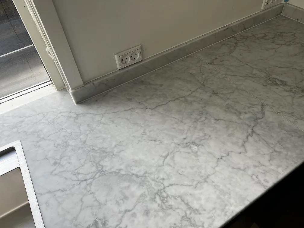 Matt Carrara C marmor runt diskzonen, med rostfri diskho i kanten och uppvikt stänkkant mot väggen i Greve.