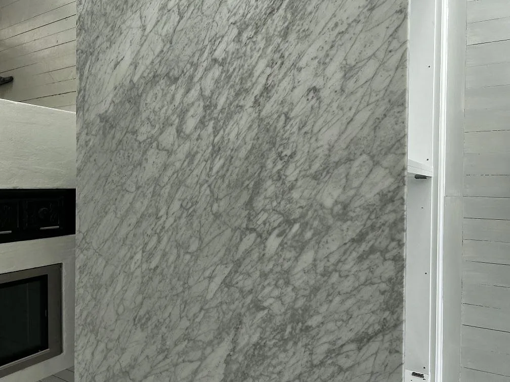 Närbild på installerad väggskiva i Carrara C marmor intill ugnsnisch i köket i Grundsund.