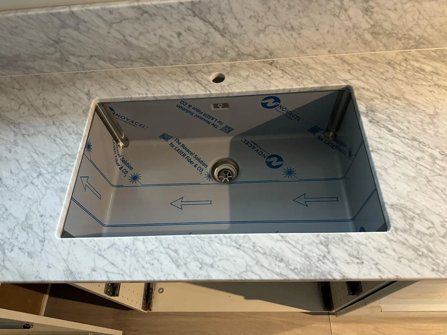 Närbild på polerad Carrara C-marmor där bänkskiva och stänkkant möts under fönstret i Höganäs.