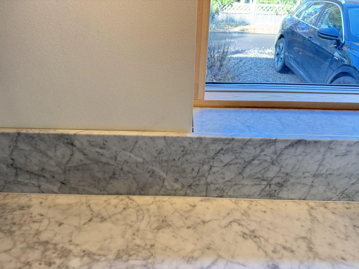 Lång fönstersida med matt Carrara C marmor som bänkskiva, stänkkant och fönsterbänk i ett kök i Höllviken.