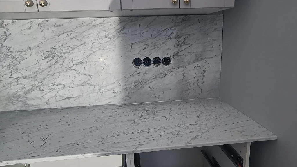 Detalj av matt Carrara C bänkskiva med matchande stenskiva och runda uttag i kök i Klagstorp.
