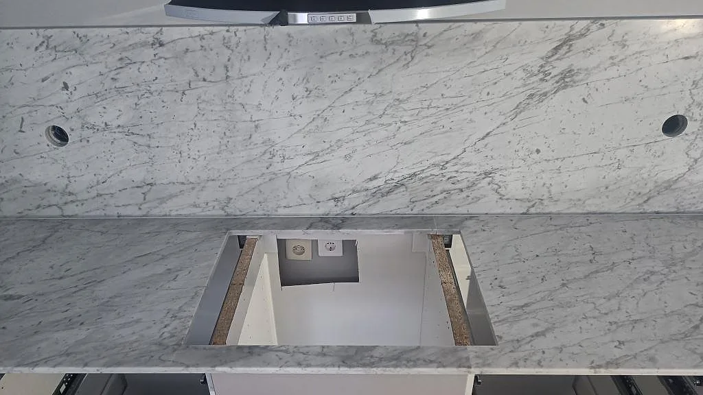 Matt marmorbänkskiva i Carrara C med hällöppning under fläkt och matchande stänkskiva i Klagstorp.