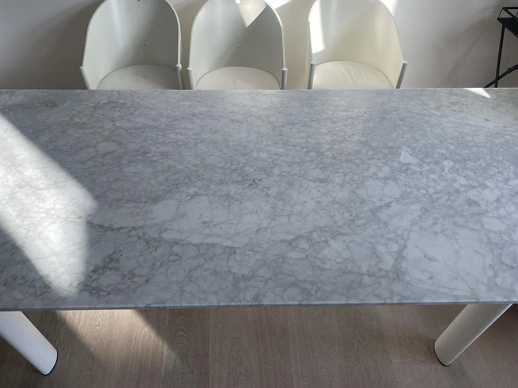 Detaljbild av ljus Carrara C marmor i matt finish som bordsskiva på vita bordsben i Köbenhavn.