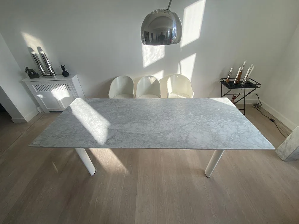 Bordsskiva i matt Carrara C marmor på vita ben i ett ljust matrum i Köbenhavn.