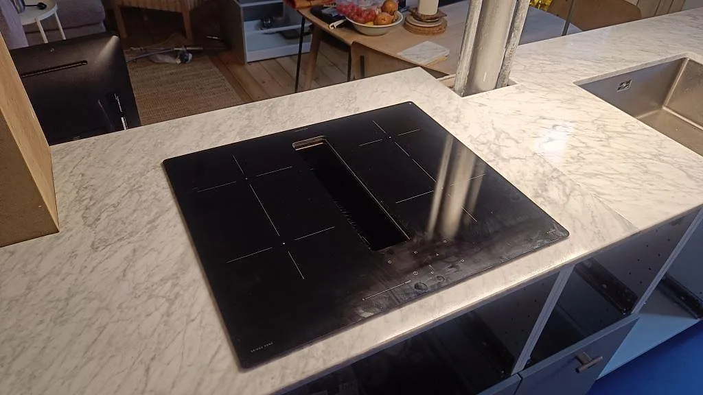 Polerad Carrara C marmorbänkskiva med svart induktionshäll och rostfri diskho under montering i ett kök i København Ø.