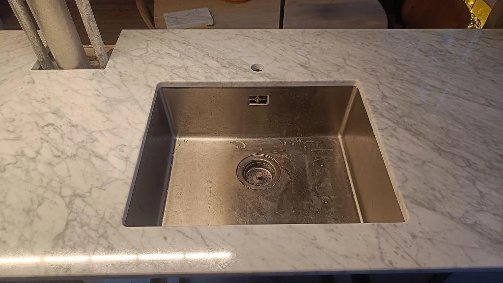 Underlimmad rostfri diskho i en polerad Carrara C marmorbänkskiva med grå ådring i København Ø.