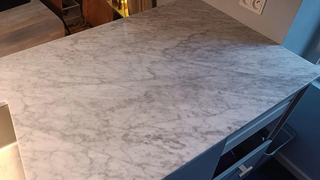 Närbild på polerad Carrara C marmor på halvön med tät grå ådring i ett kök i København Ø.