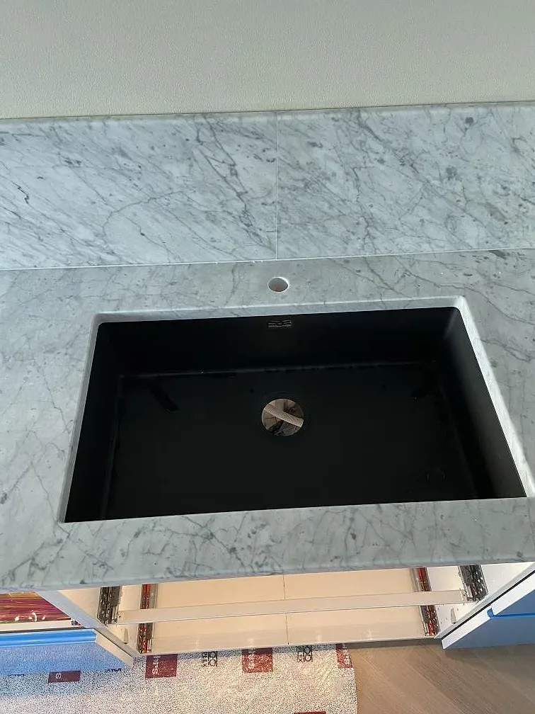 Svart underlimmad kompositdiskho infälld i köksbänkskiva av Carrara C marmor med tydlig grå ådring i Landskrona.