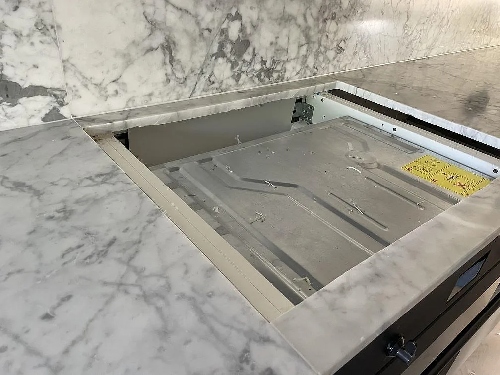 Förberett hälluttag i matt Carrara C-marmor med matchande stänkskydd bakom bänkskivan i Lindome.