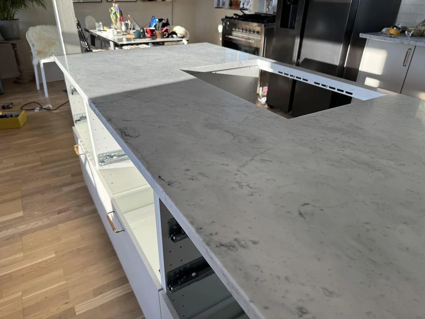 Låg vinkel över köksö i matt Carrara C marmor med hälluttag och synlig ådring i Löddeköpinge.