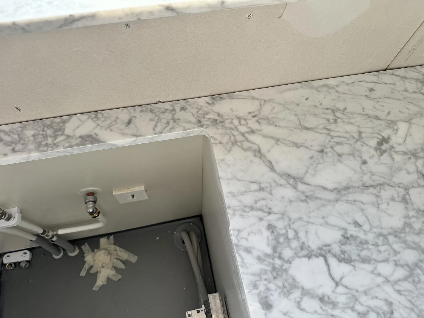 Polerad marmorbänkskiva i Carrara C med öppen stomme och synligt rörarbete i badrum i Lomma.