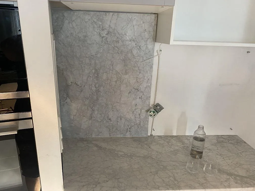 Bänkskiva i Carrara C marmor med marmorvägg och eluttag, fotograferad under montering i ett kök i Malmö.