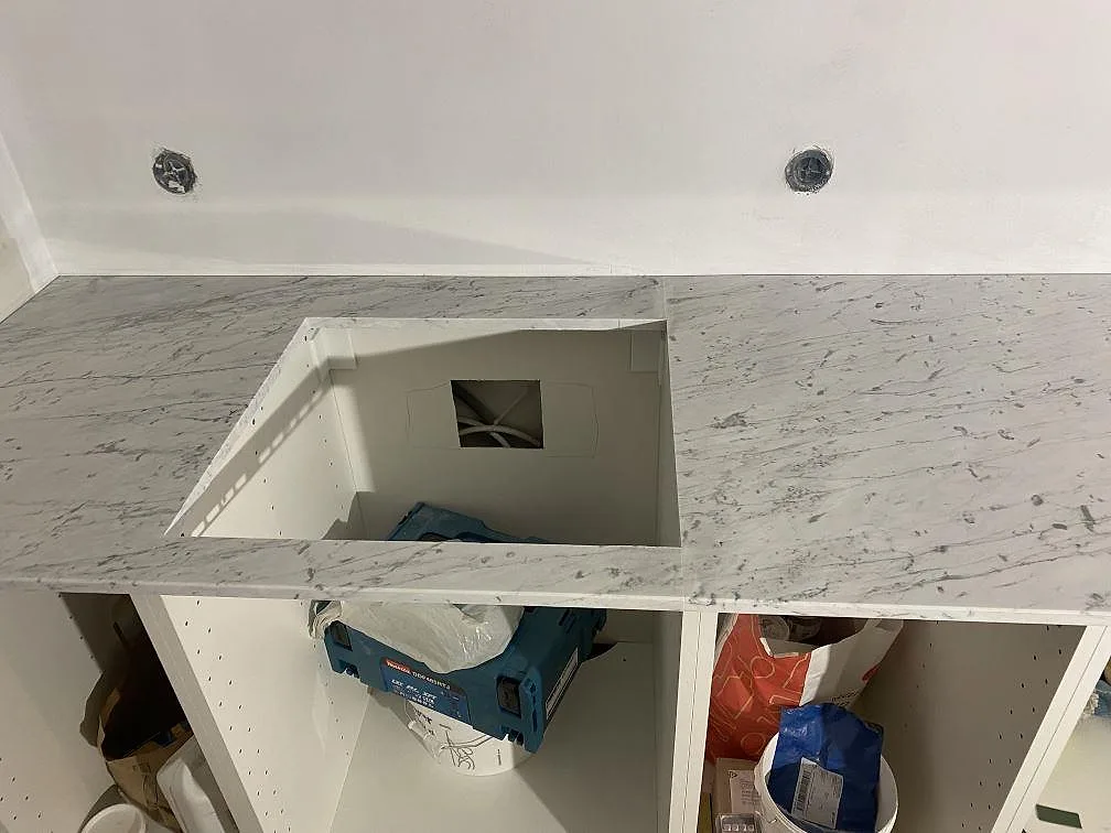 Köksbänkskiva i matt Carrara C marmor sedd ovanifrån med urtag i ett kök under montering i Malmö.