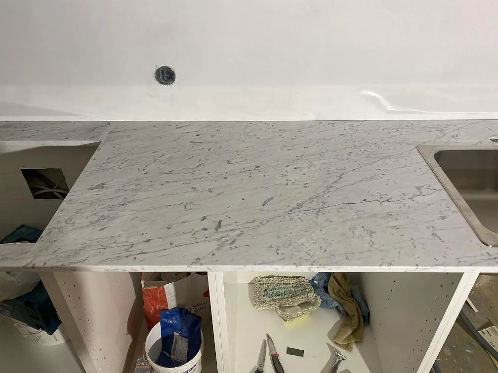 Ovanifrån på en köksbänkskiva i matt Carrara C marmor med rostfri diskho och urtag i ett kök i Malmö.