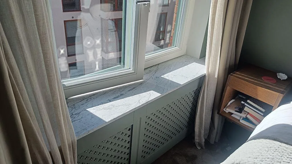 Carrara C-marmor som fönsterbänk med matt finish ovanpå en radiatorskärm vid fönstret i ett sovrum i Malmö.