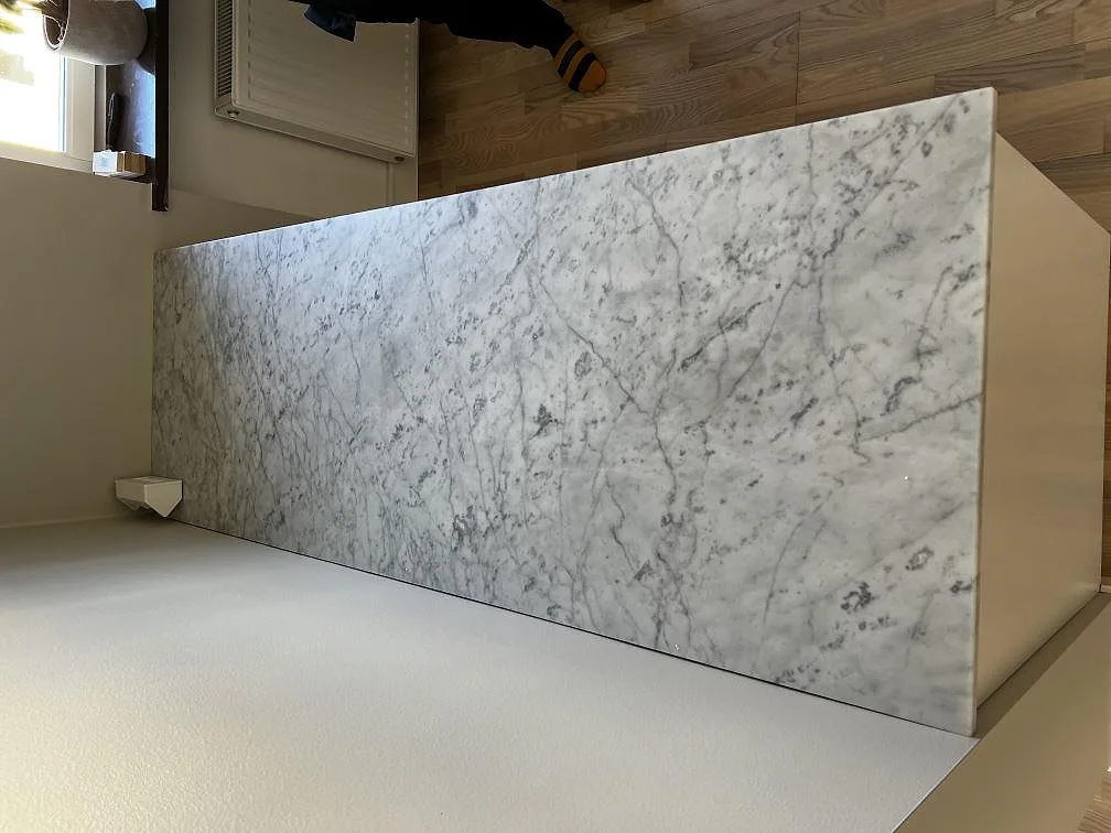 Köksö i vit Carrara C marmor med grå ådring, matt yta, fotograferad under montering i ett kök i Malmö.