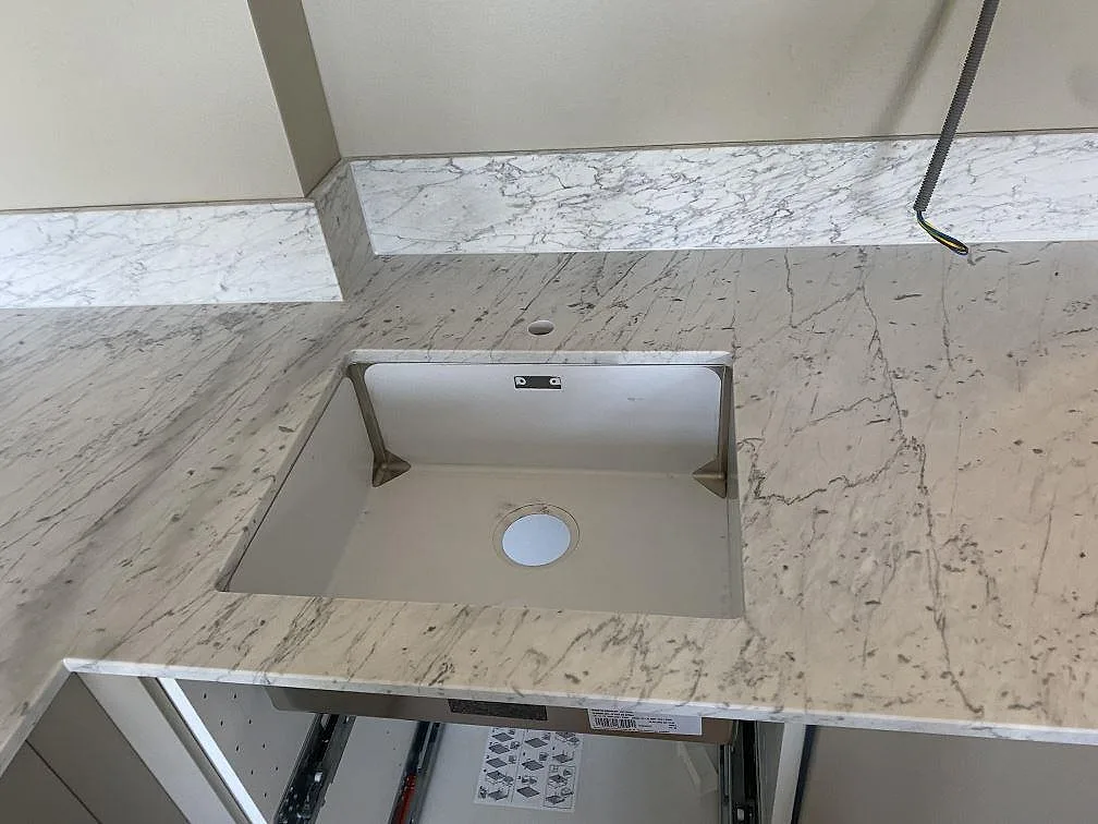 Underlimmad diskho i en vit Carrara C marmorbänkskiva med fönsterbänk i samma sten i ett kök i Malmö.