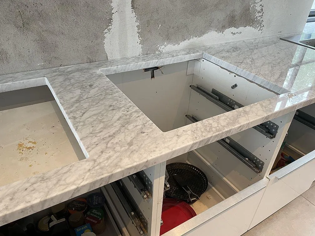 Närbild på polerad Carrara C köksbänkskiva med bearbetade urtag och öppen köksinredning i Malmö.