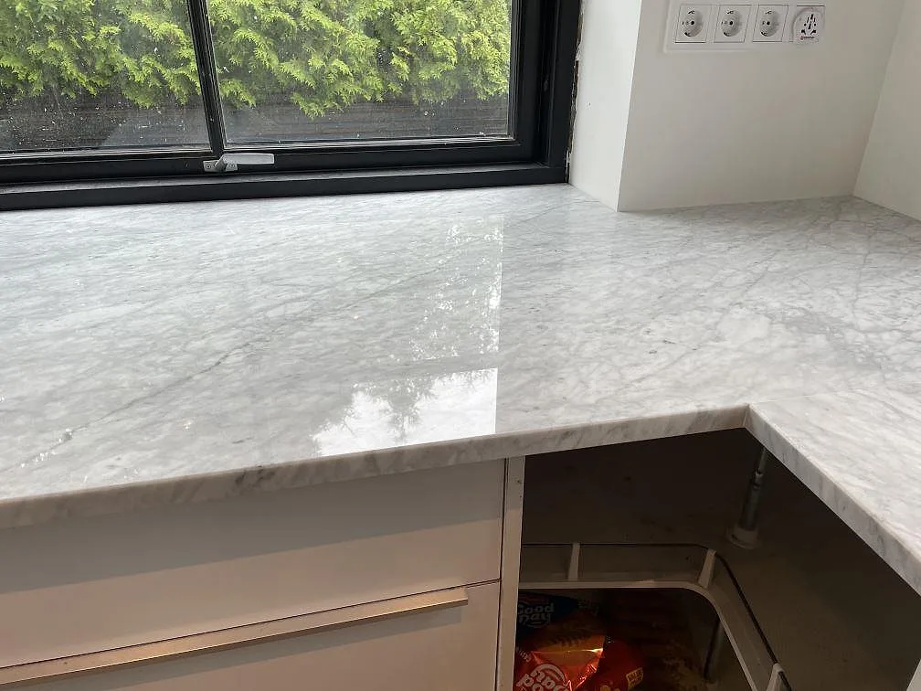 Carrara C marmorbänkskiva, polerad, med hörn vid svart fönster och ljus ådring i Malmö.