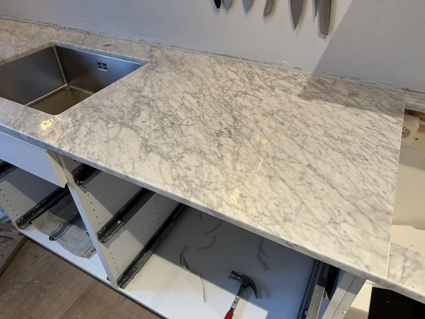 Köksbänkskiva i polerad Carrara C marmor med underlimmad rostfri diskho och hälluttag i ett kök i Malmö.