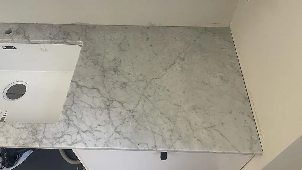 Detalj av polerad Carrara C bänkskiva i marmor vid underlimmad diskho i Malmö.