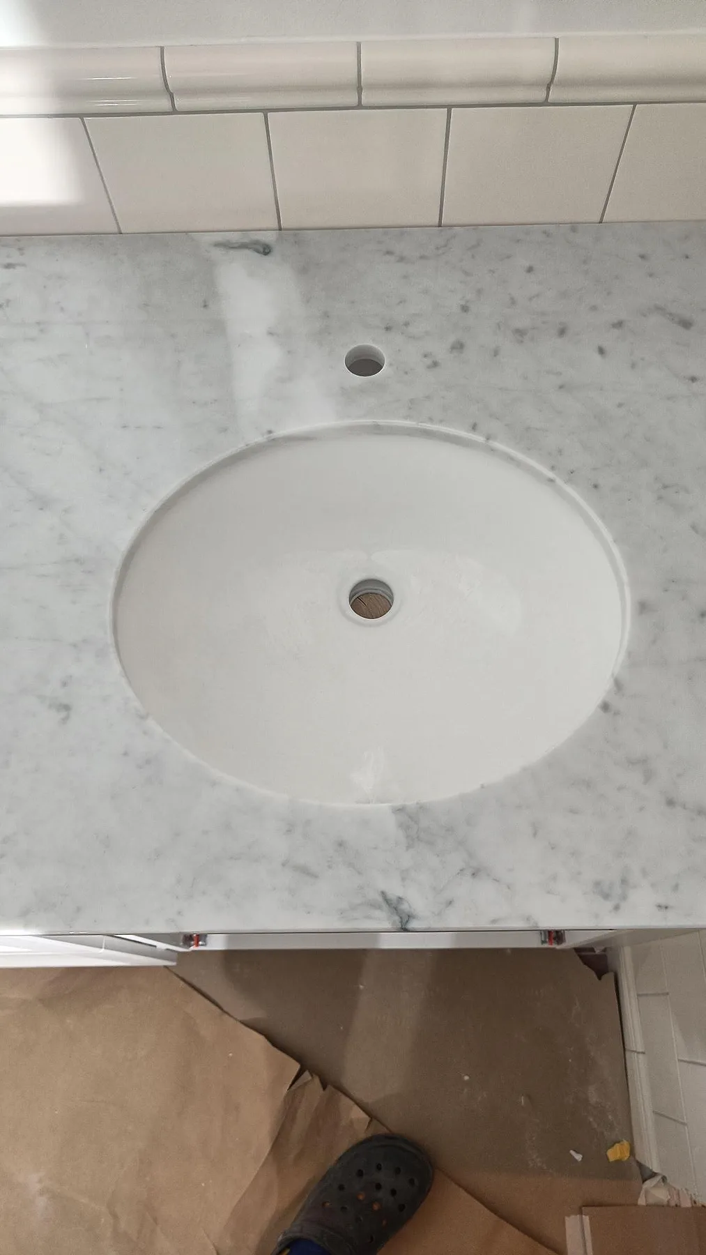 Detalj av polerad Carrara C marmor vid rund tvättställsskål och blandarhål i badrum i Malmö.