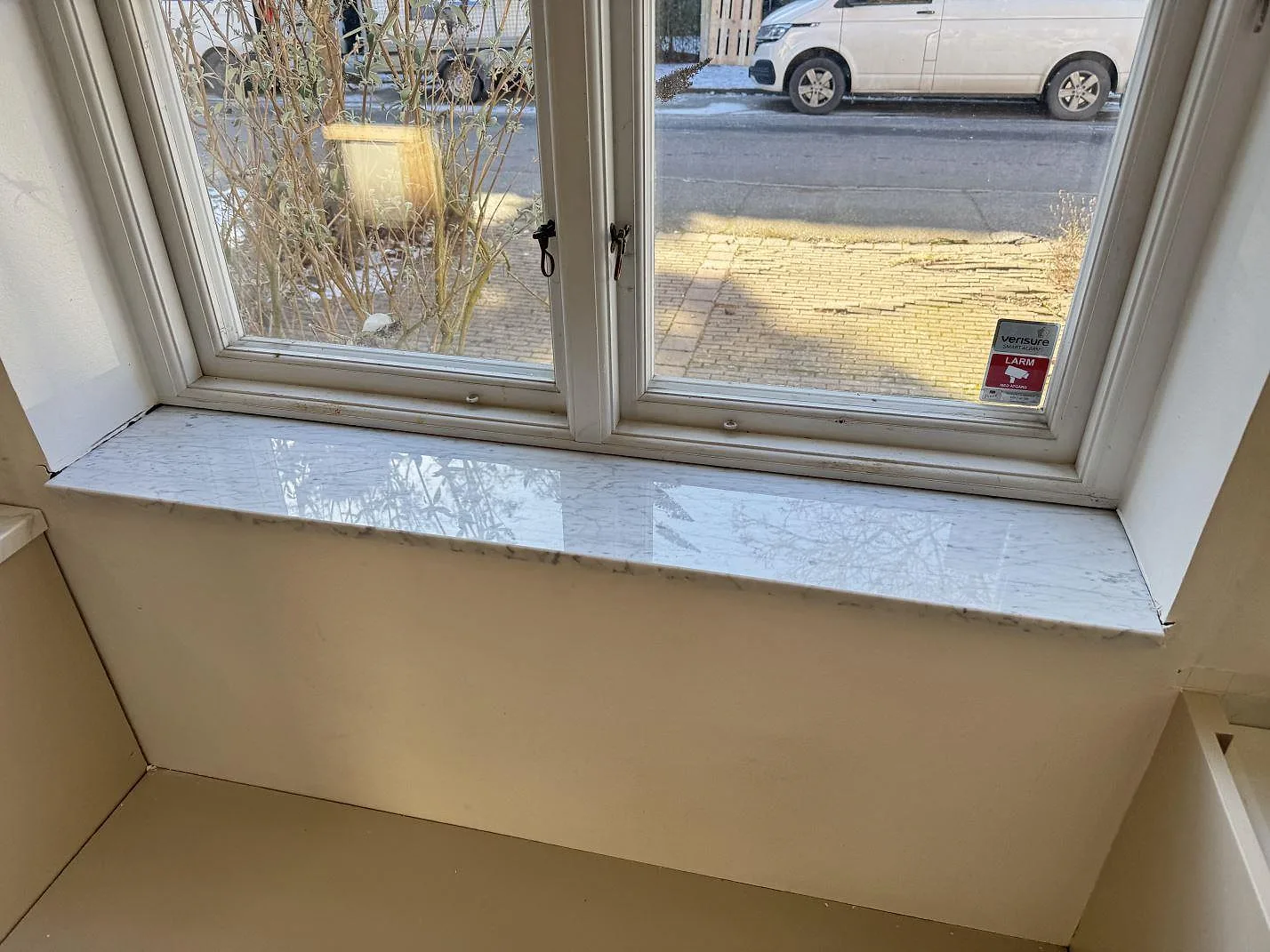Fönsterbänk i vit Carrara C-marmor, polerad, monterad under fönster med vinterljus i Malmö.