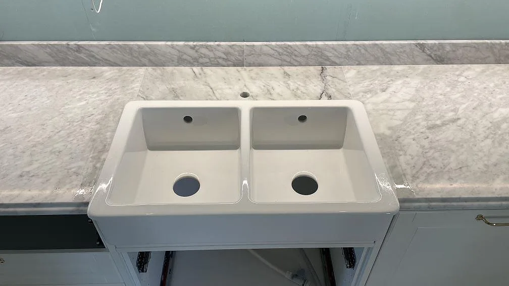 Matt köksbänkskiva i Carrara C marmor med vit dubbelho och uppvikt stänkkant i ett kök i Malmö.