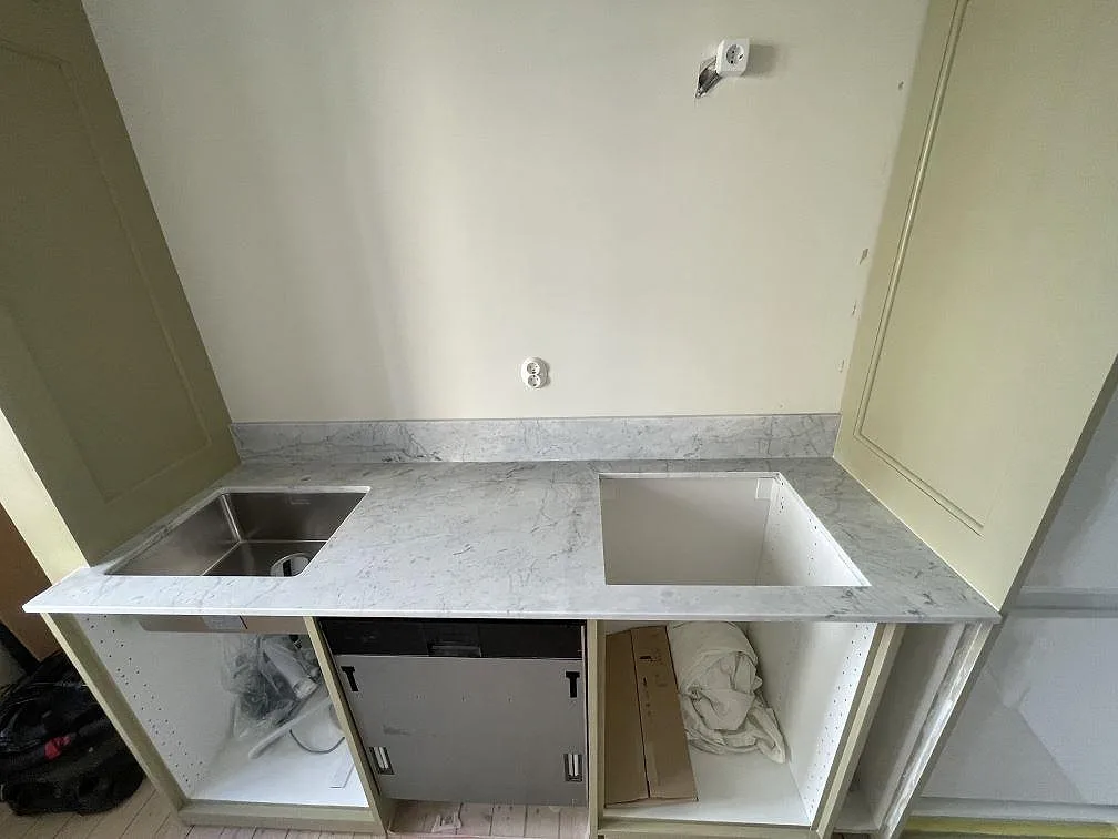 Köksbänkskiva i vit marmor Carrara C, matt, med underlimmad rostfri diskho och urtagning för häll i ett kök i Malmö.