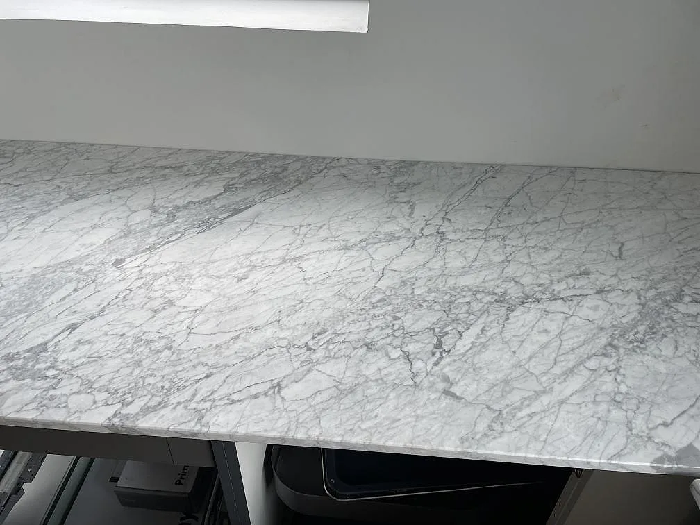 Matt Carrara C marmor som köksbänkskiva med tydlig grå ådring under ett fönster i Mölndal.